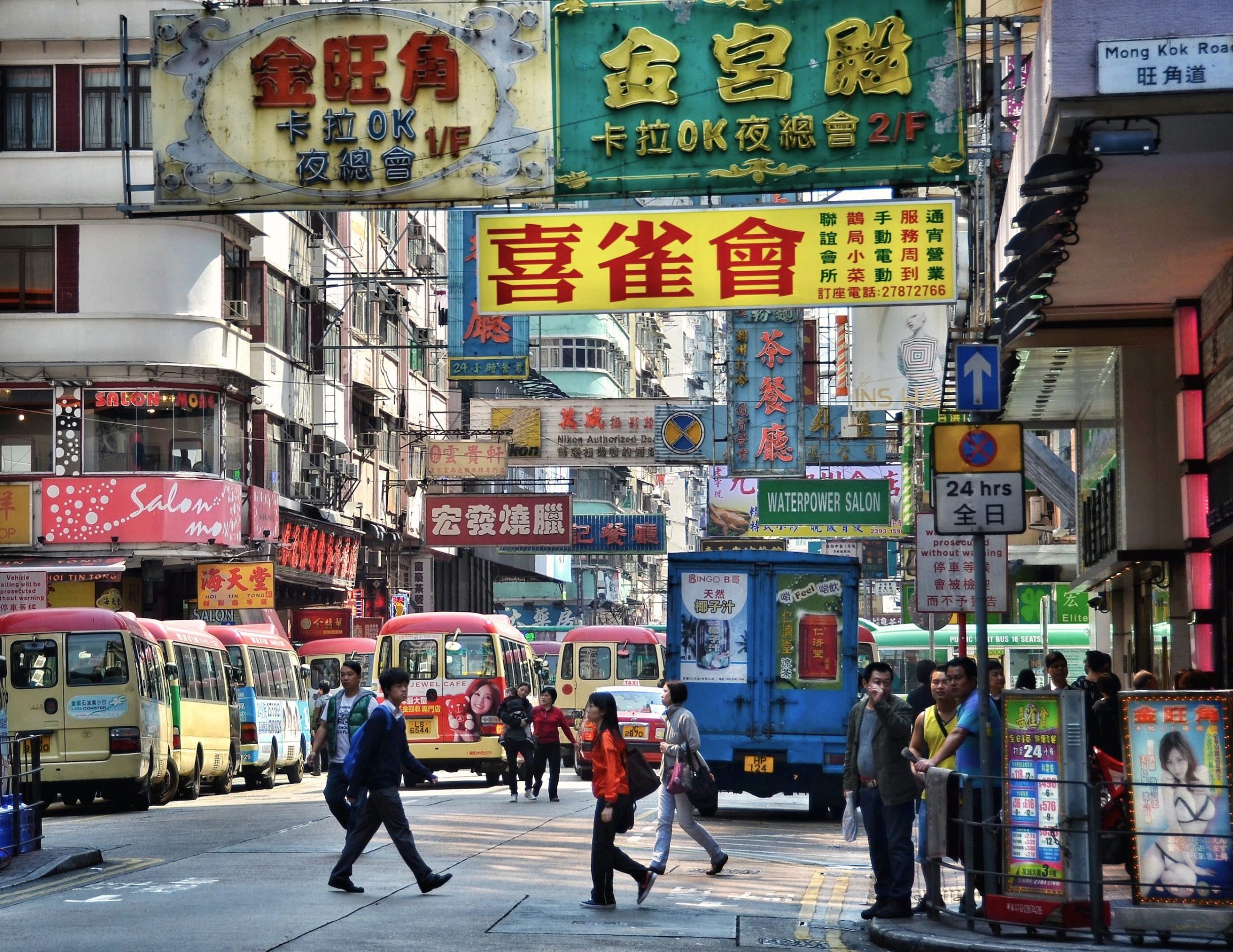 Busy street scene with many neon signs,buses and people crossing the streets