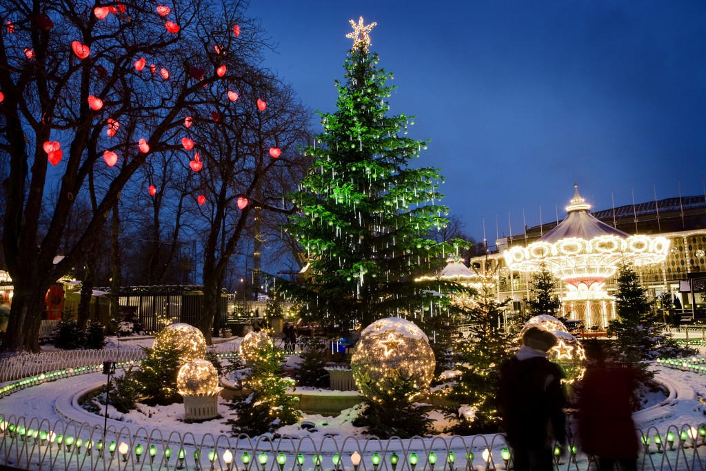 A large Christmas tree with a star atop it surrounded by lighted up glass balls in the grounds of the Tivoli Amusement Park, Denmark