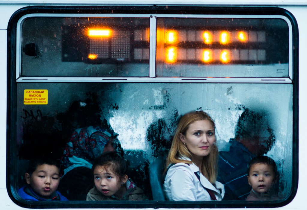 Faces of a woman and three children in a bus window in Kyrgyzstan