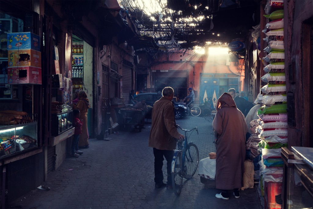 Man with cycle walking away in an alleyway in Marrakesh