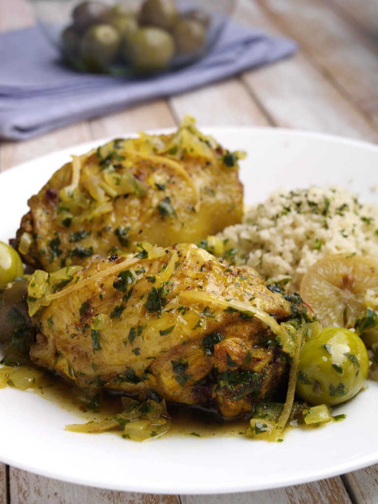 A plate of chicken tagine with coucous and a bowl of olives in the background, Morocco