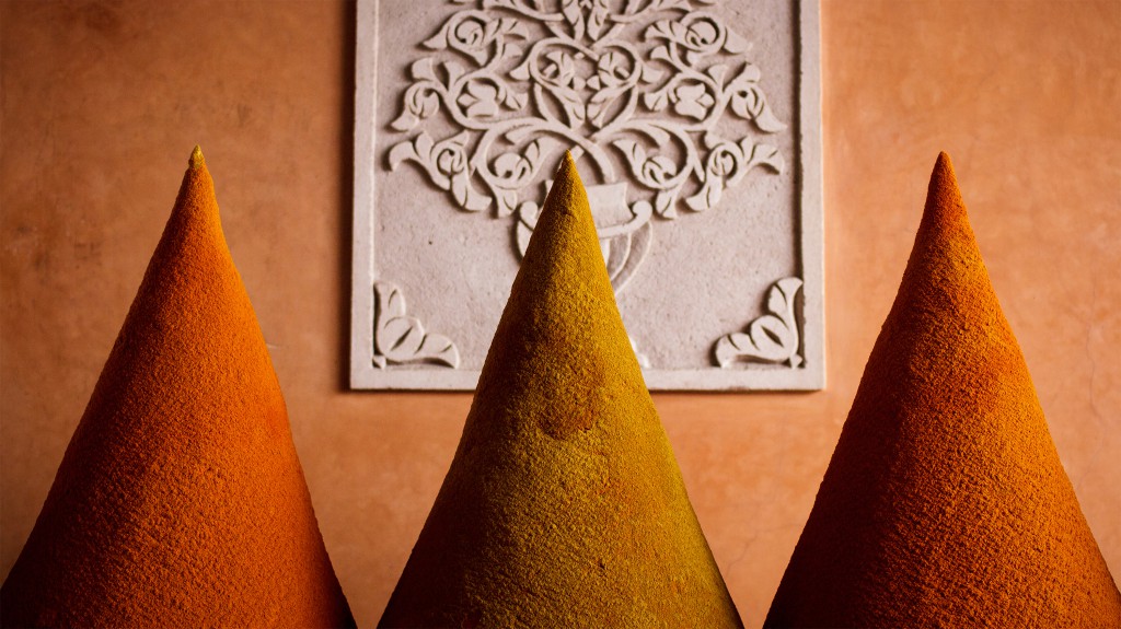 Spice-powder in three conical piles against a bas relief wall, Marrakech, Morocco