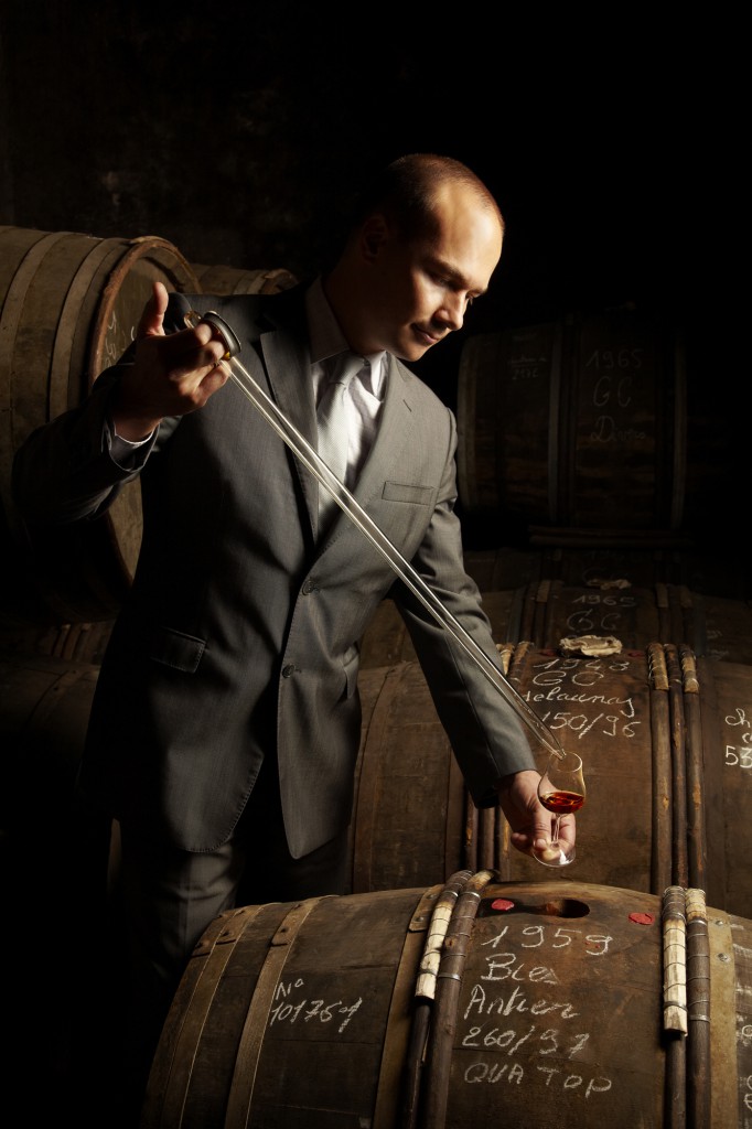 Benoit Fil, Martell Cellar Master drawing wine from a cask into a wine glass with a pipette in Cognac, France