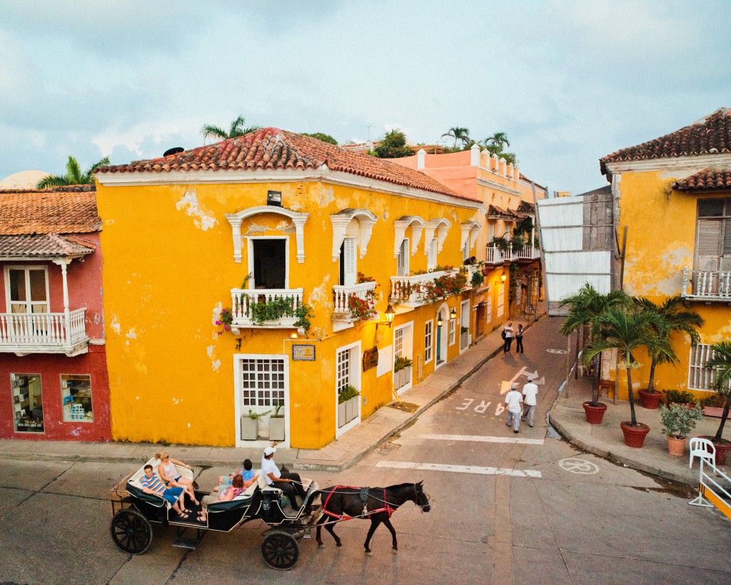 A family strolls by in a horse-drawn carriage outside La Vitrola, one of the iconic restaurants along the outside walls. of Cartagena, Colombia.