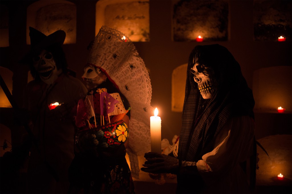 Person in skull mask and cowl eerily lighted up by their candle at Day of the Dead, Mexico