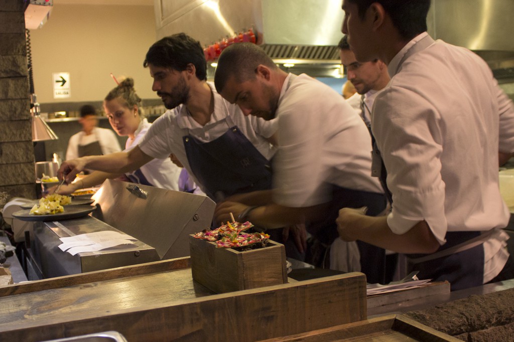 Virgilio in a group of chefs plating a dish in Central's kitchen