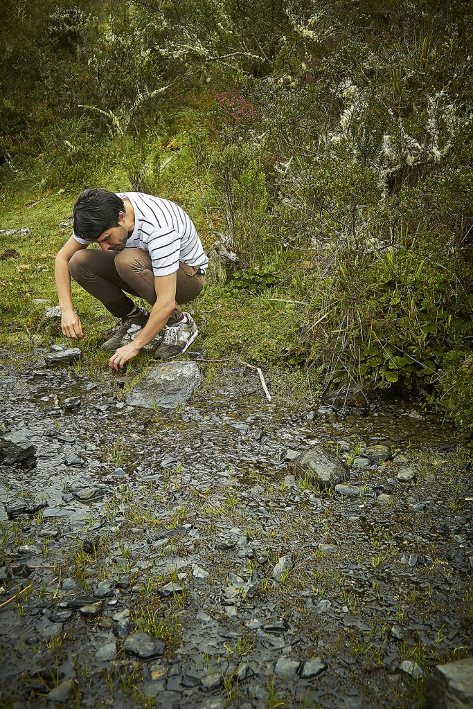 Virgilio Martinez squatting by a shallow, stony rivulet foraging for edible clay, etc, Peru