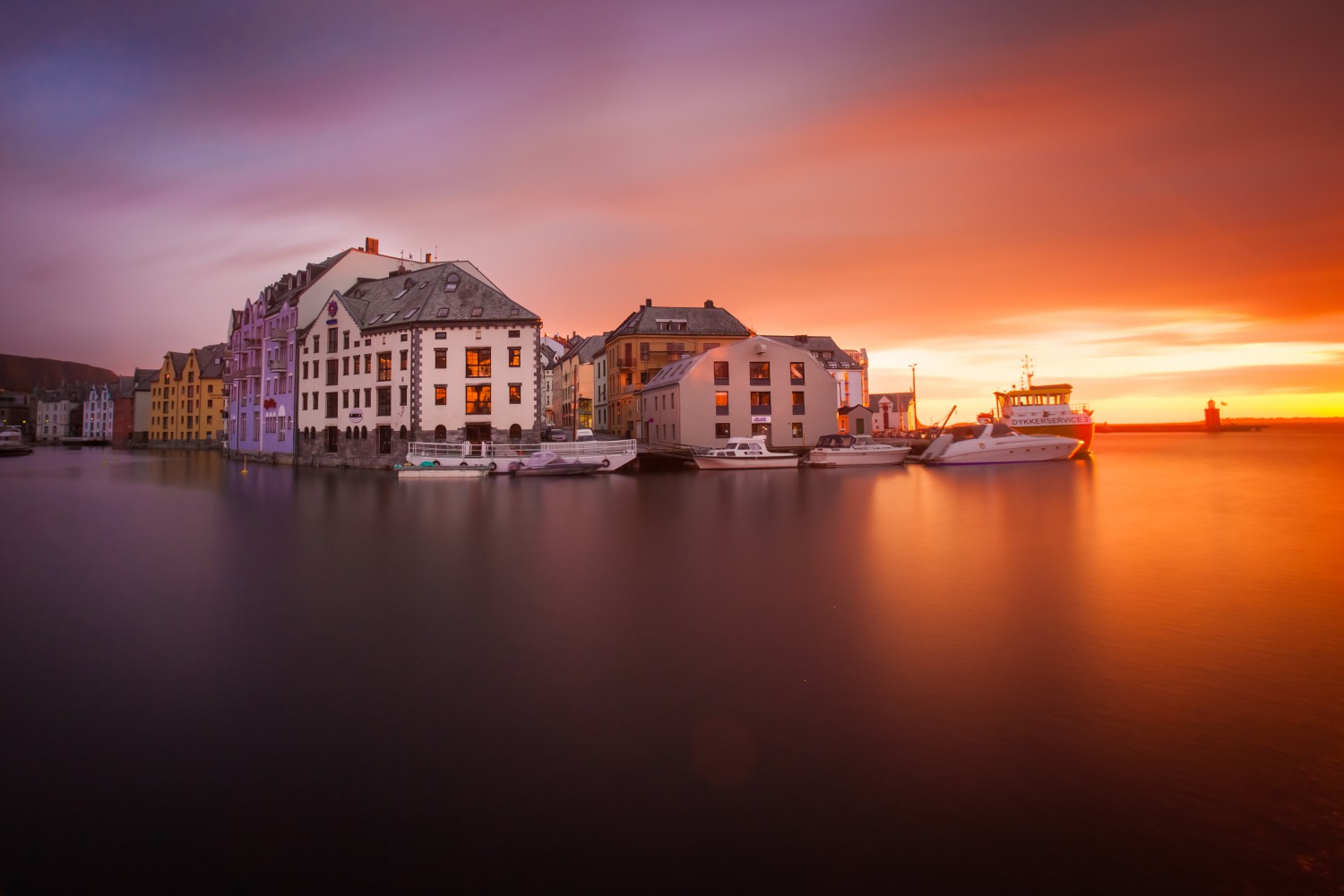 The sun setting behind the art nouveau buildings along Alesund's waterfront lights up the sky in myriad hues
