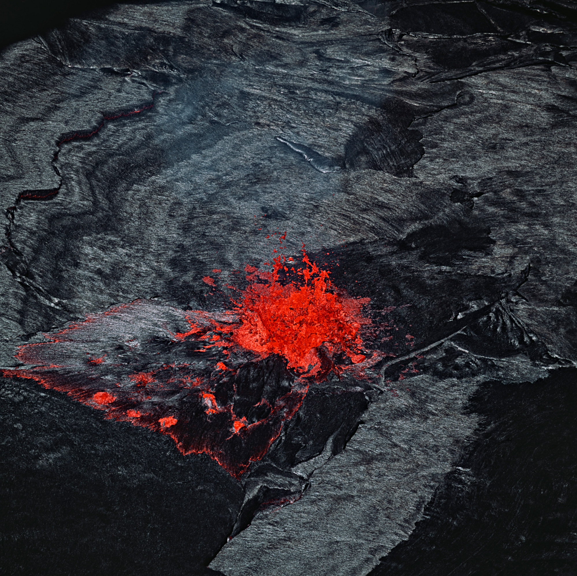 A bright red eruption against its black stony landscape at Rincon de la Vieja, Costa Rica 