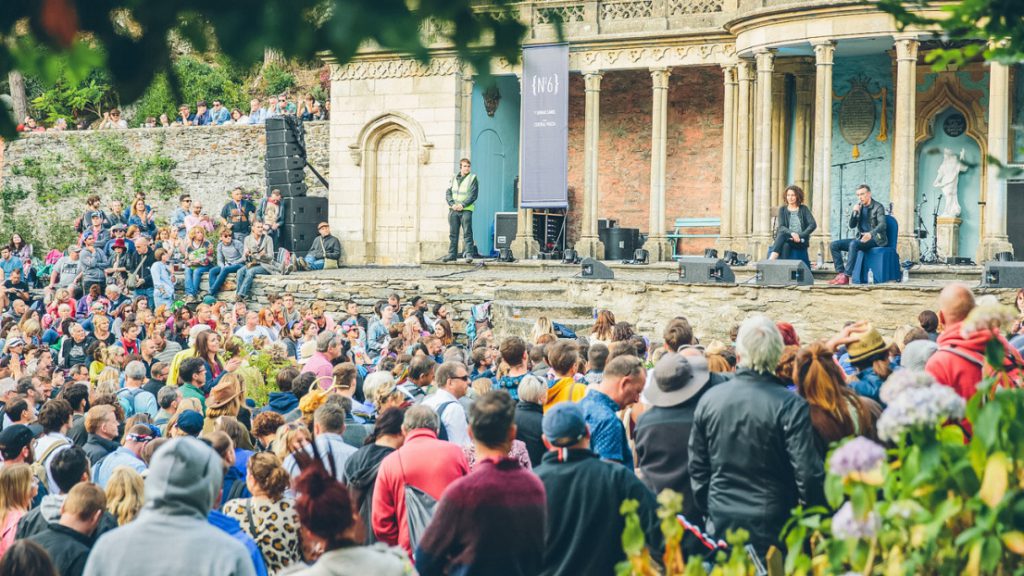 Audience watching a band perform outside a colonnaded building