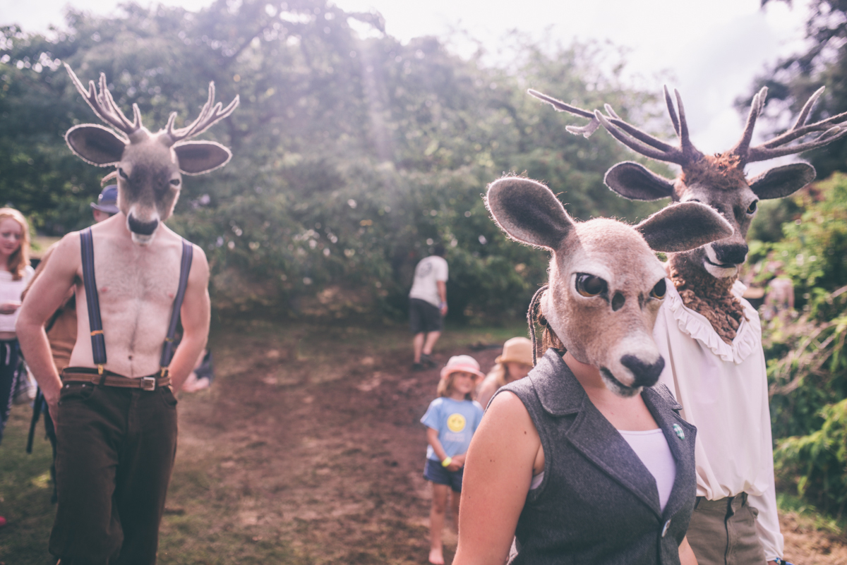 A trio walking by wearing whole deer head masks
