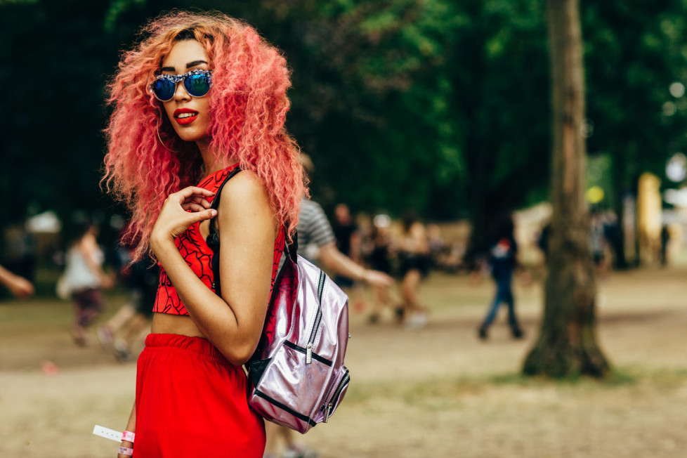Girl with red curly hair and dressed all in red with silvery pink backpack at the Lovebox festival