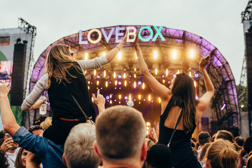 Two girls riding shoulders and clapping in front of the Lovebox stage