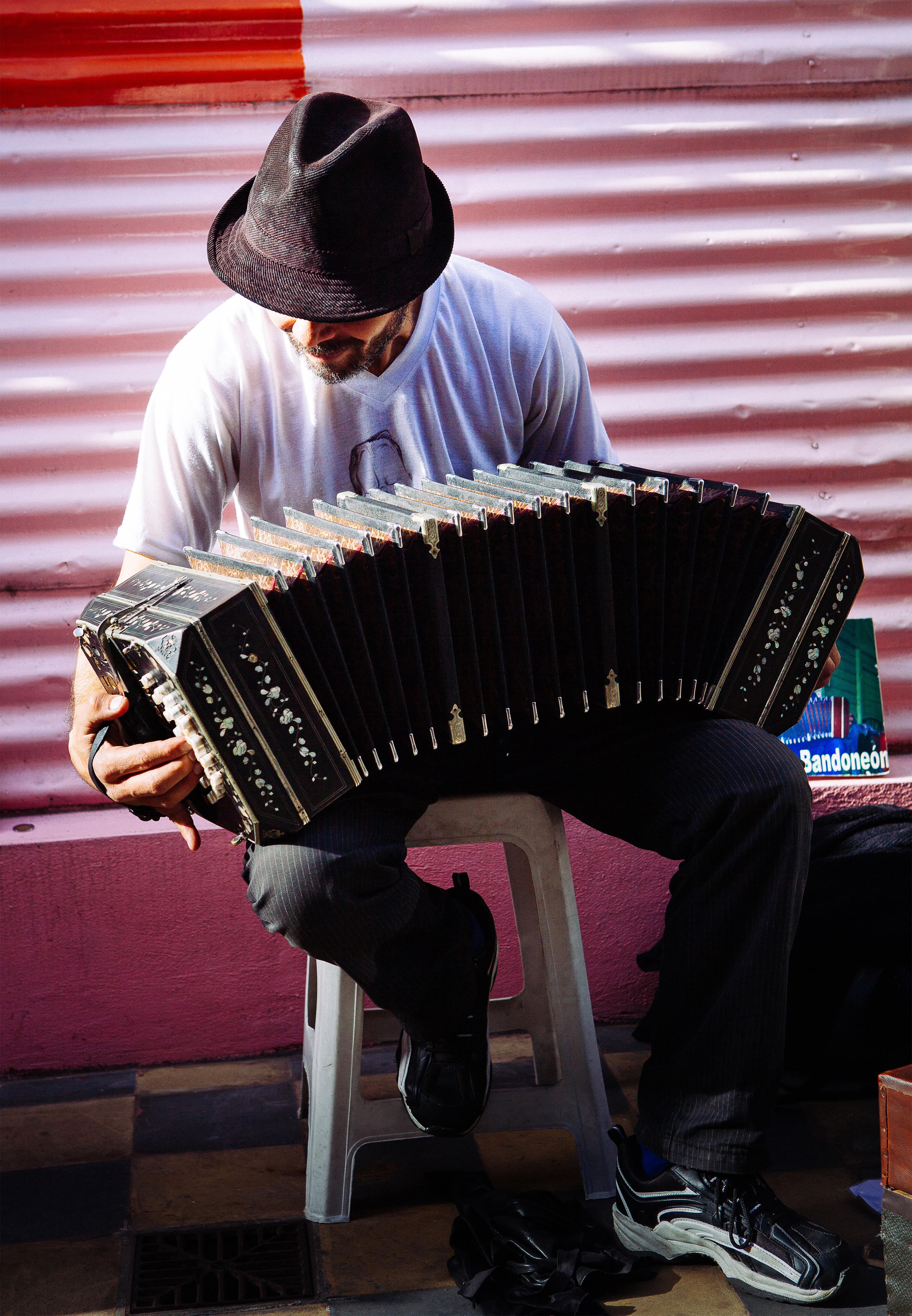 Domingo, a bandoneonista sitting on a stool and playing the bandoneon 