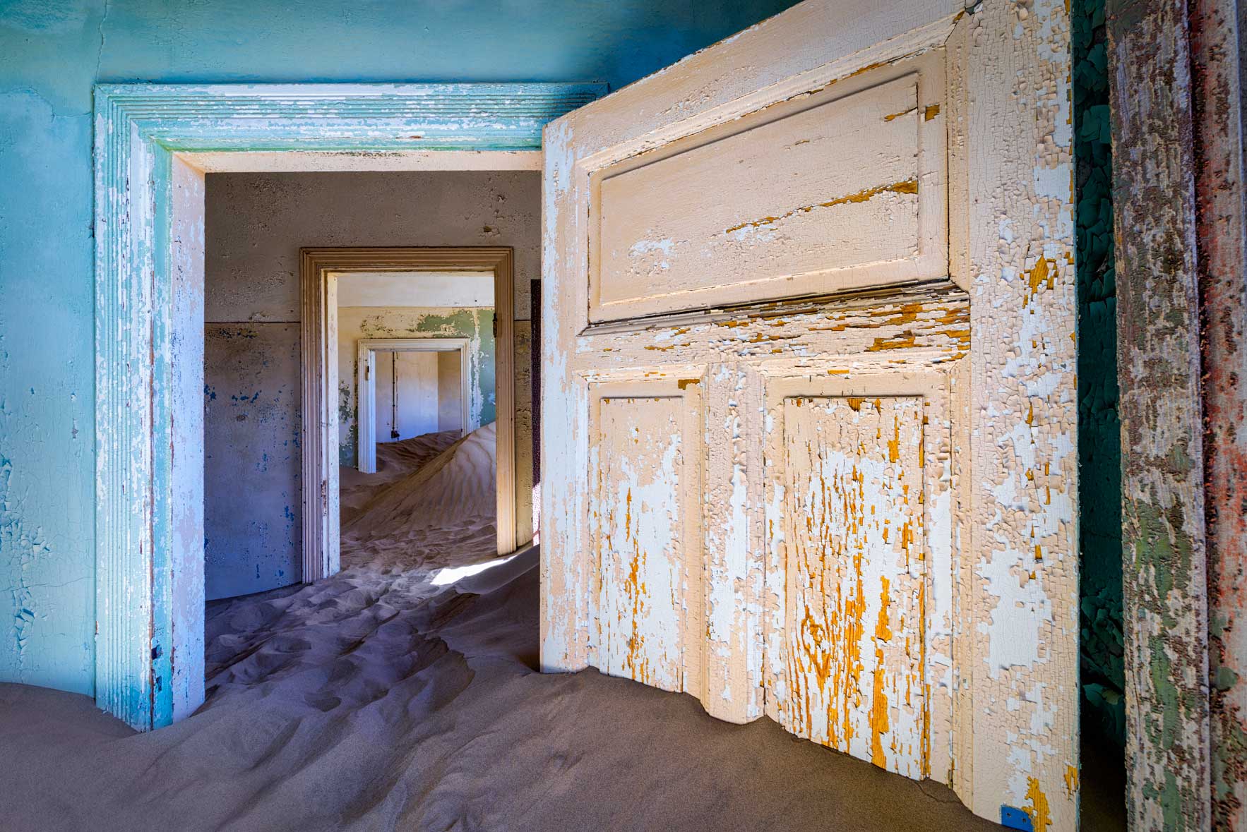 Sand filled rooms seen through a series of doorways in Kolmanskop, Namibia