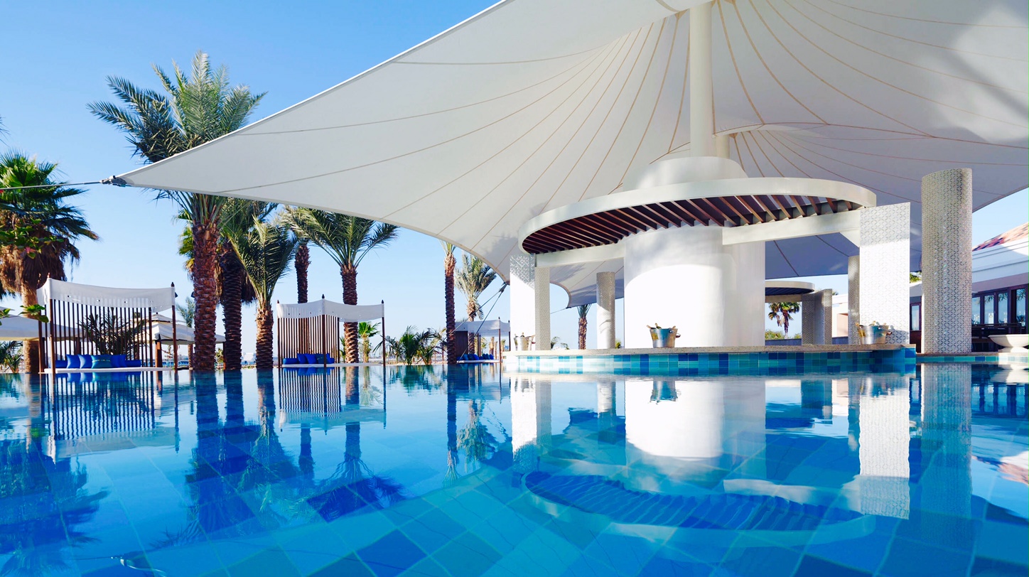 View across a very blue pool to Lai Baie Lounge Bar and its white canopy, Ritz Carlton, Dubai