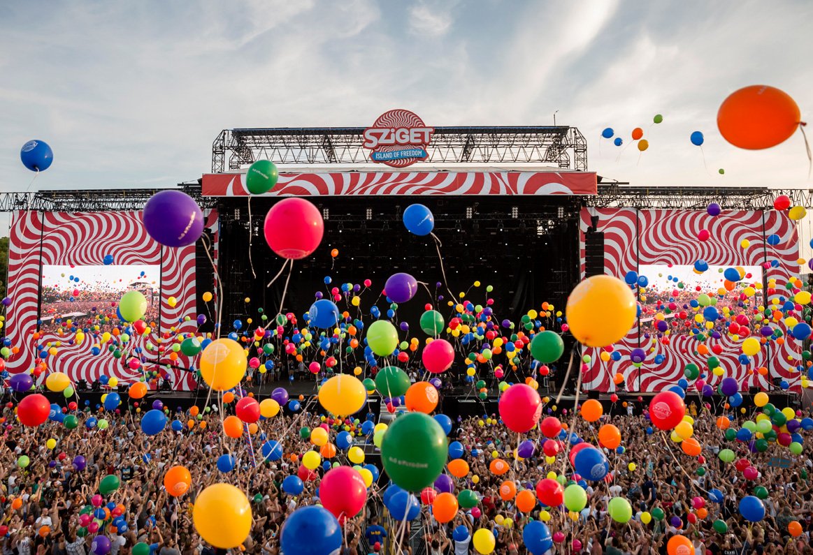 Crowd releases colourful balloons into the sky in front of the main Sziget stage