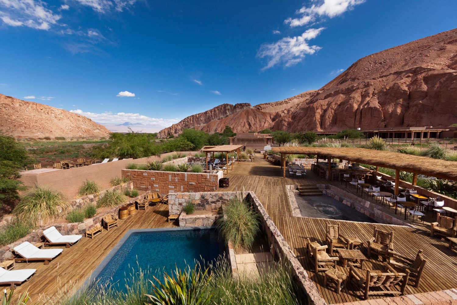 The pool, wooden decking and loungers at Alto Atacama Lodge, Chile with mountains in the backdrop