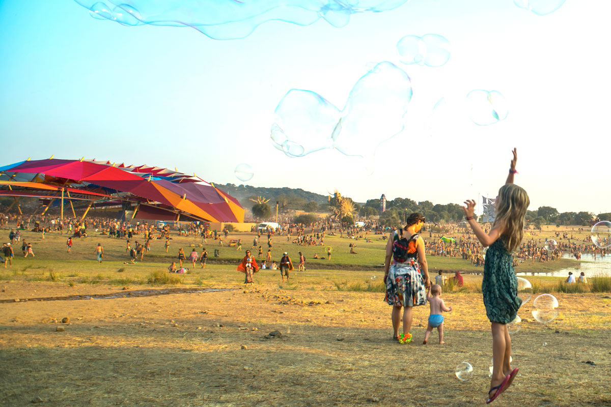 Two children chasing giant floating bubbles at Boom Festival, Portugal