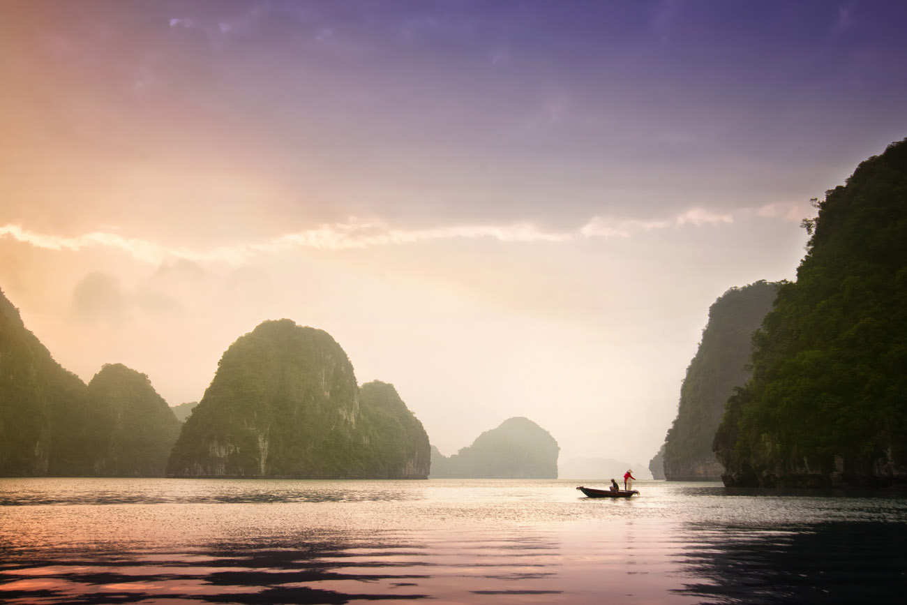 Dreamy shot of a fishing boat on still water surrounded by limestone islands