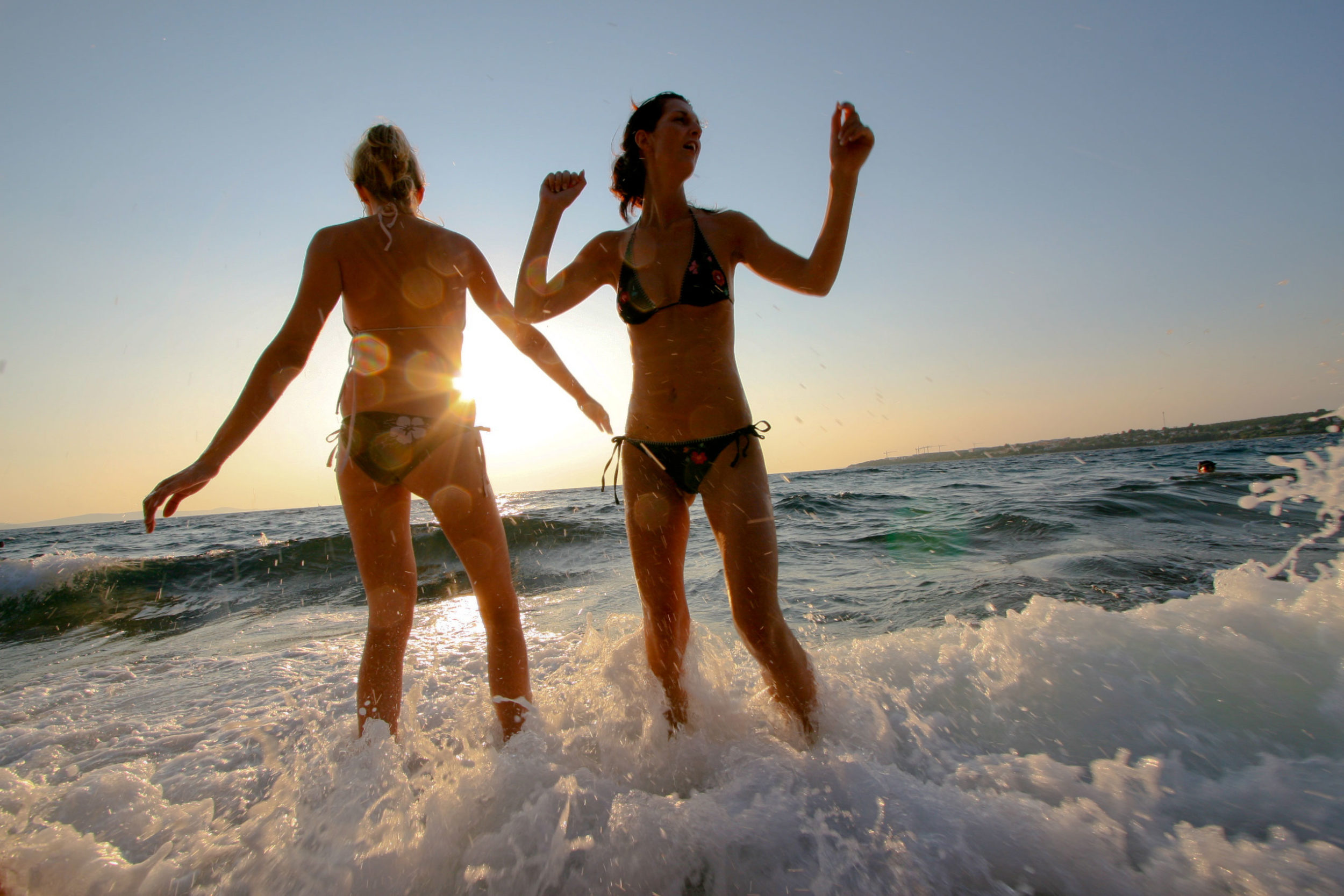 Two girls dancing in the surf at Tisno
