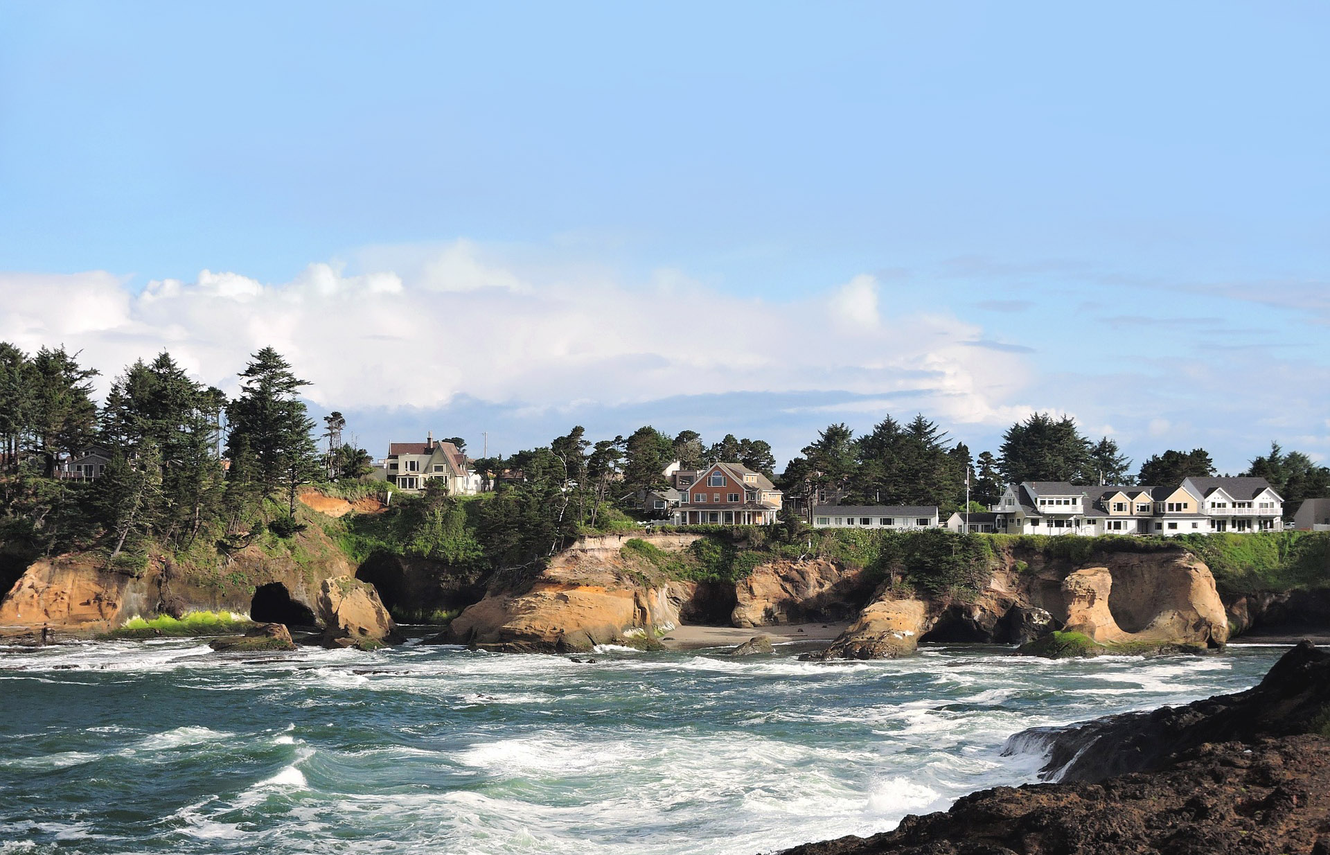 Houses set on a cliff above the rough sea, Oregon, USA