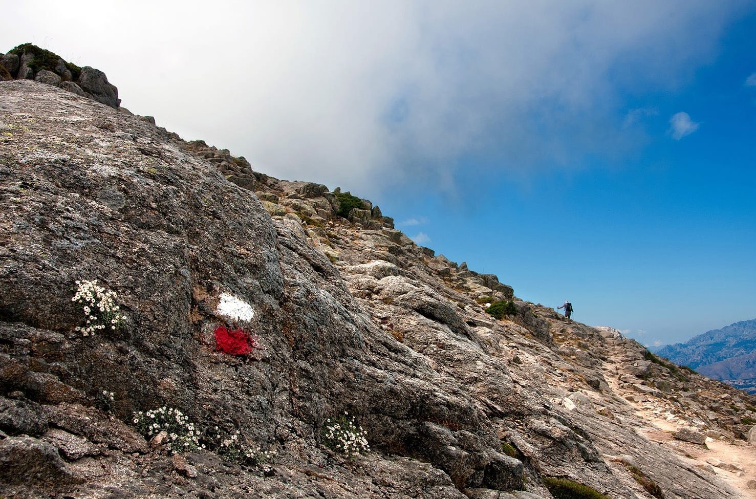 Red and white paint daubed on a rock on a very rocky mountainside in Corsica