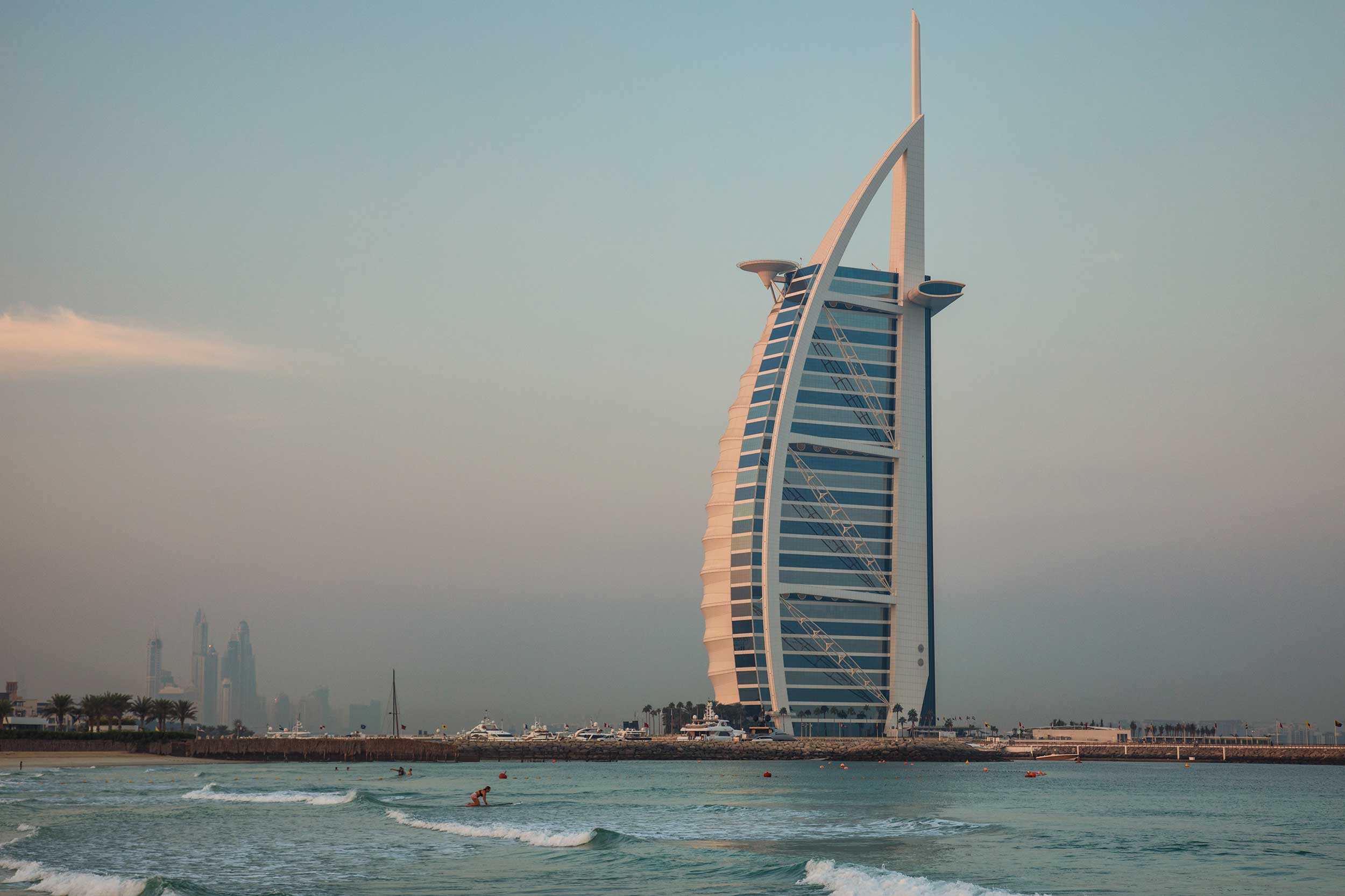 View across the sea of a tall building in the shape of a dhow's sail in Dubai