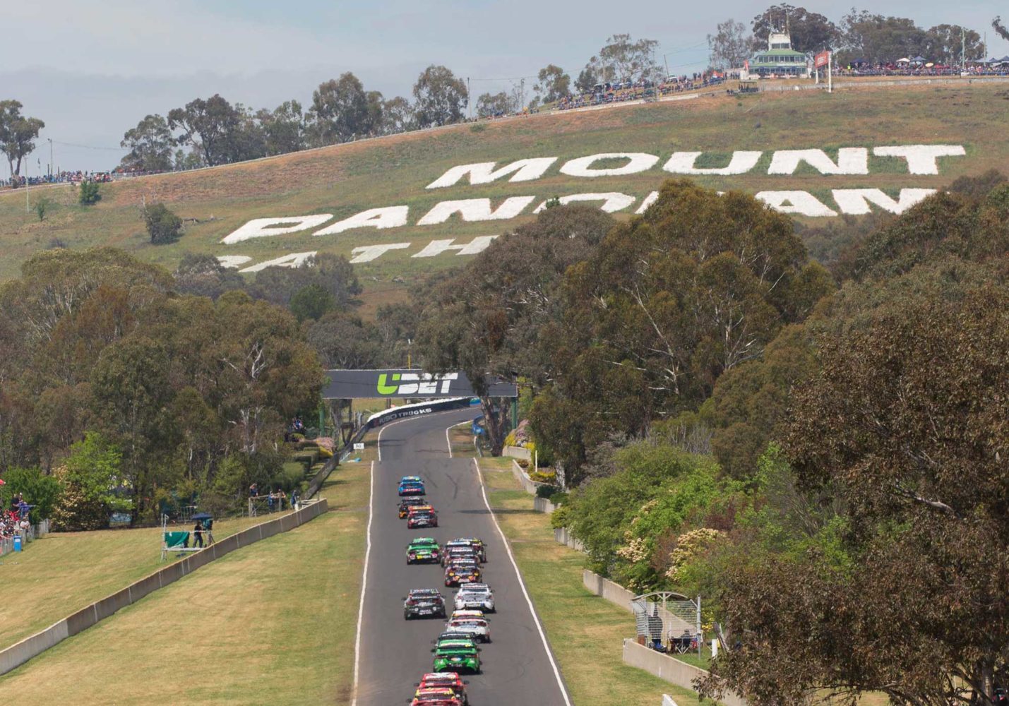 Row of V8 supercars heading towards Mount Panorama at the Supercheap Bathurst 1000, Australia