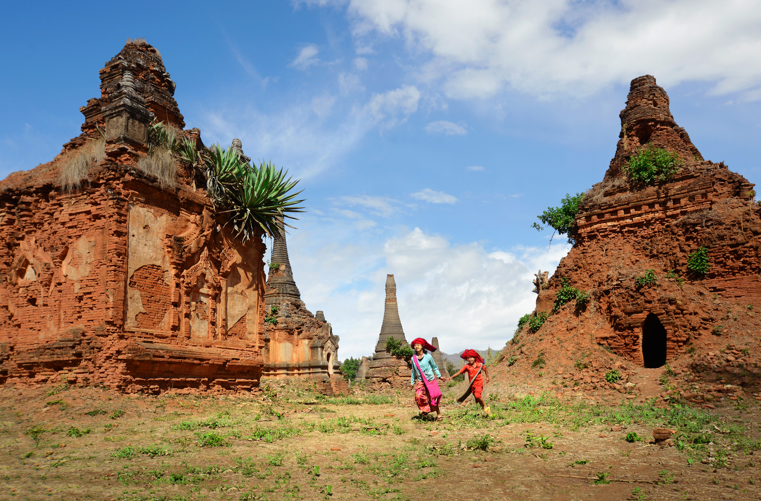 Two children running between crumbling brick stupas in Myanmar
