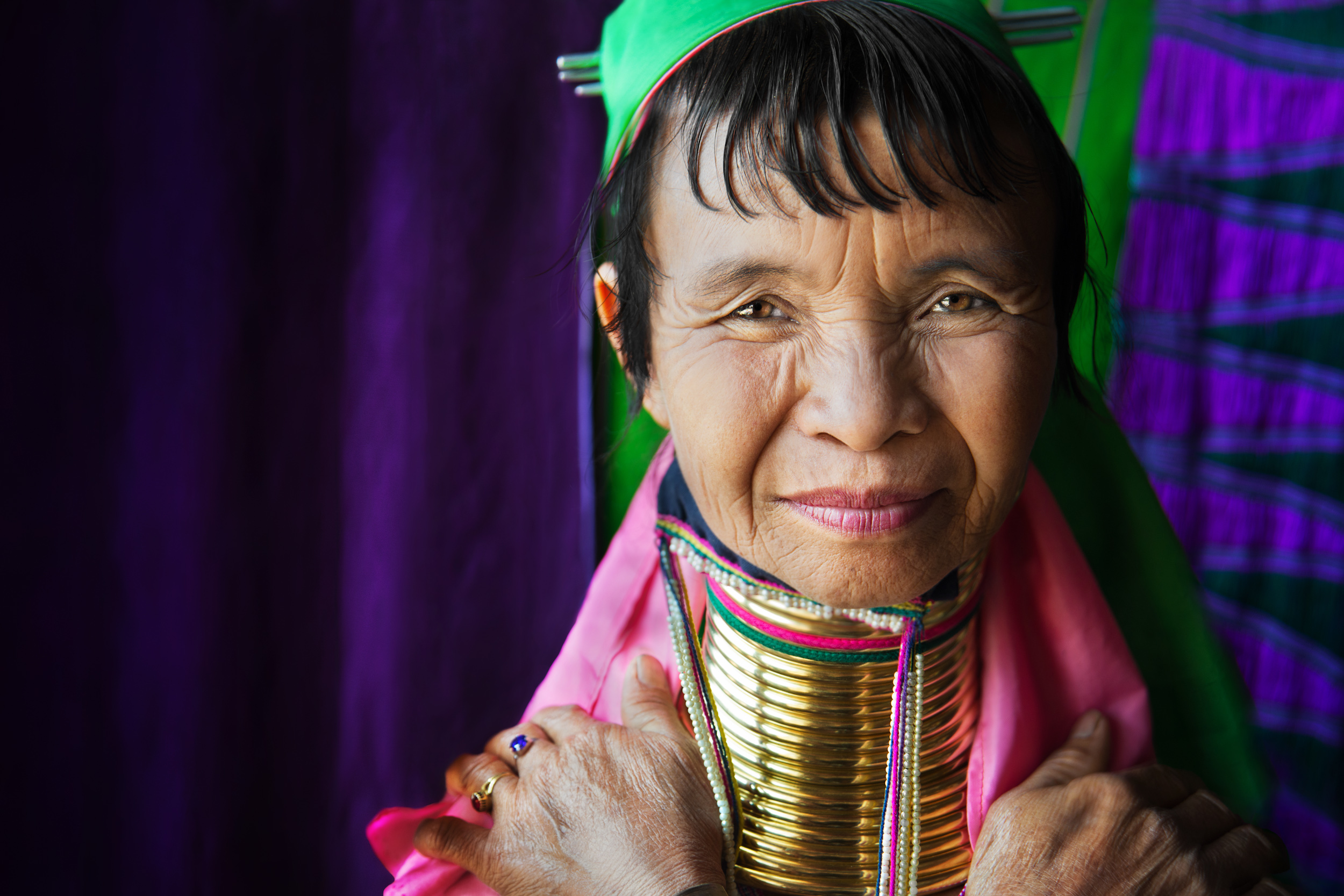 Close-up of a local tribal woman in a green head scarf and brass rings up her neck