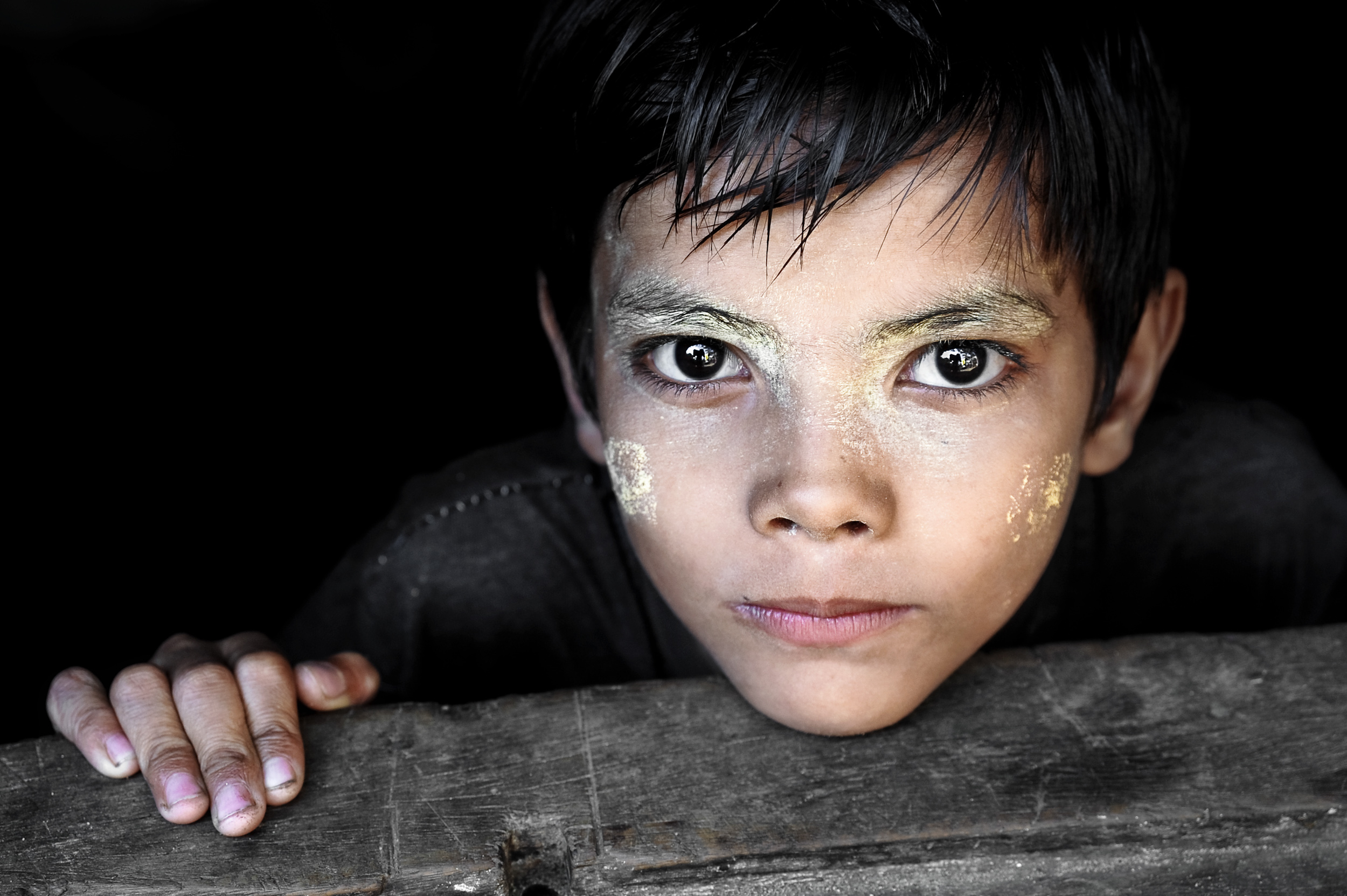 Close-up of a boy's face with white sandalwood paste designs on his cheeks and forehead, Myanmar