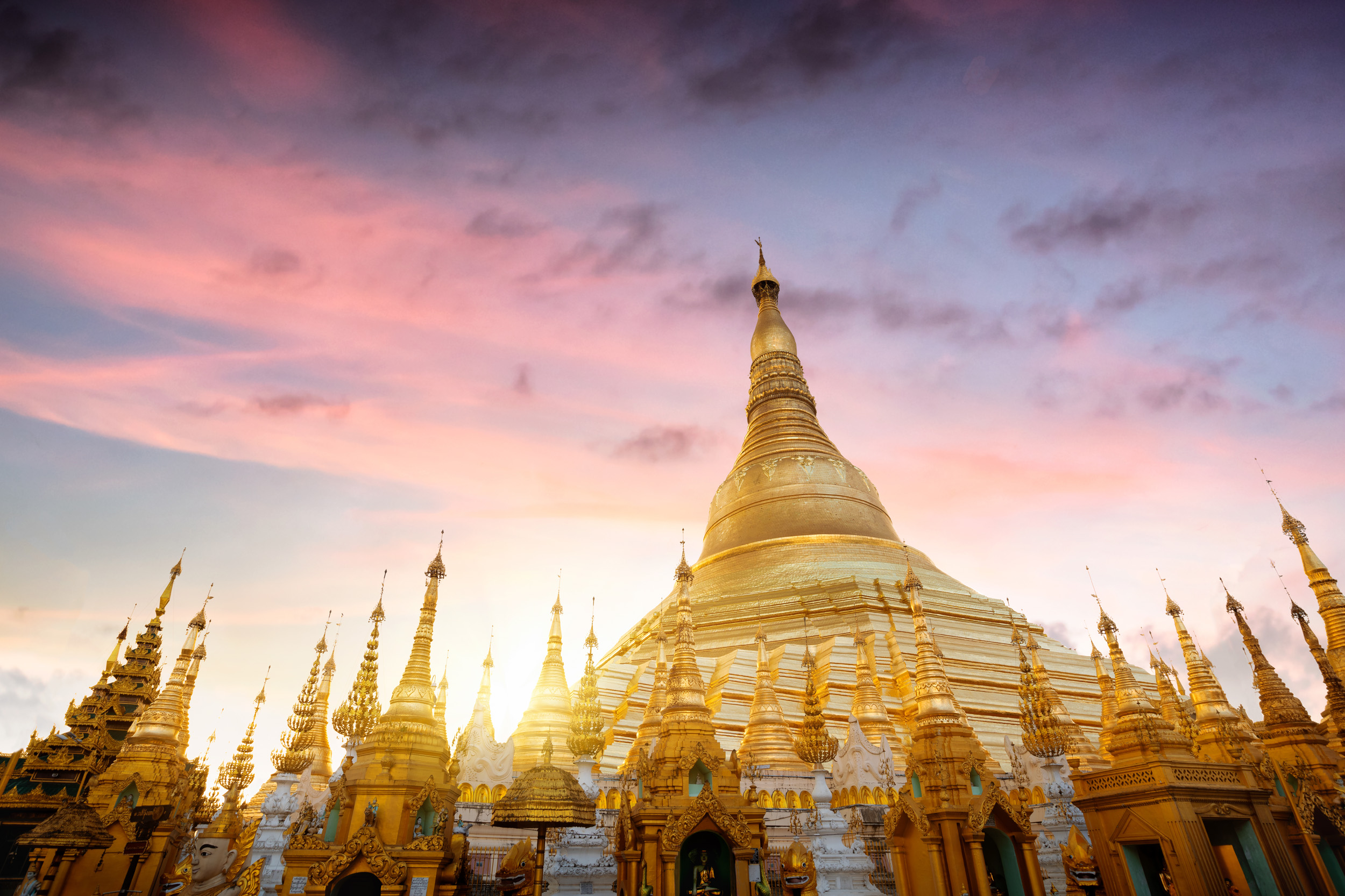 A large golden temple surrounded by smaller spires, at sunset