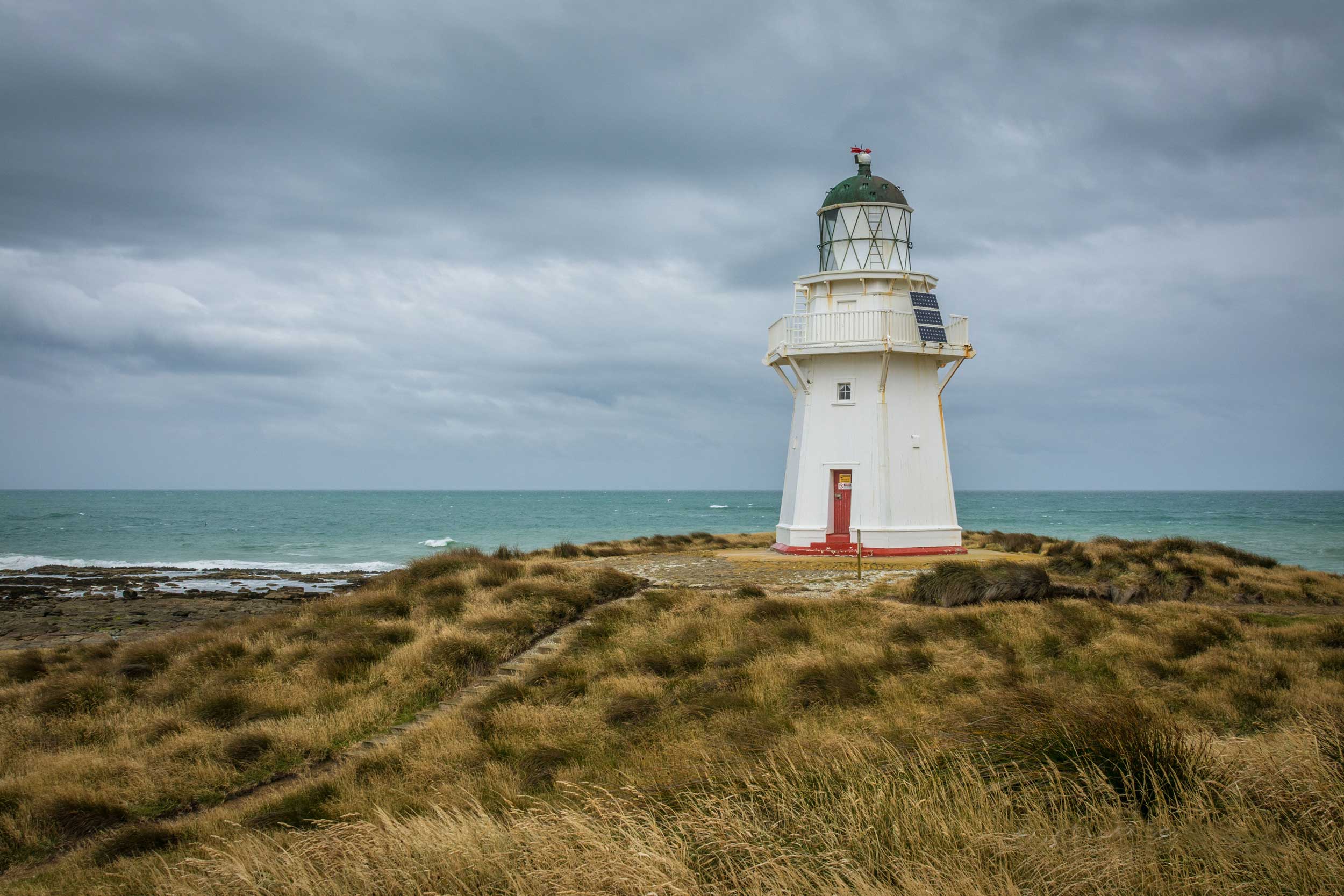 White lighthouse against a dark sky with sea visible in the background