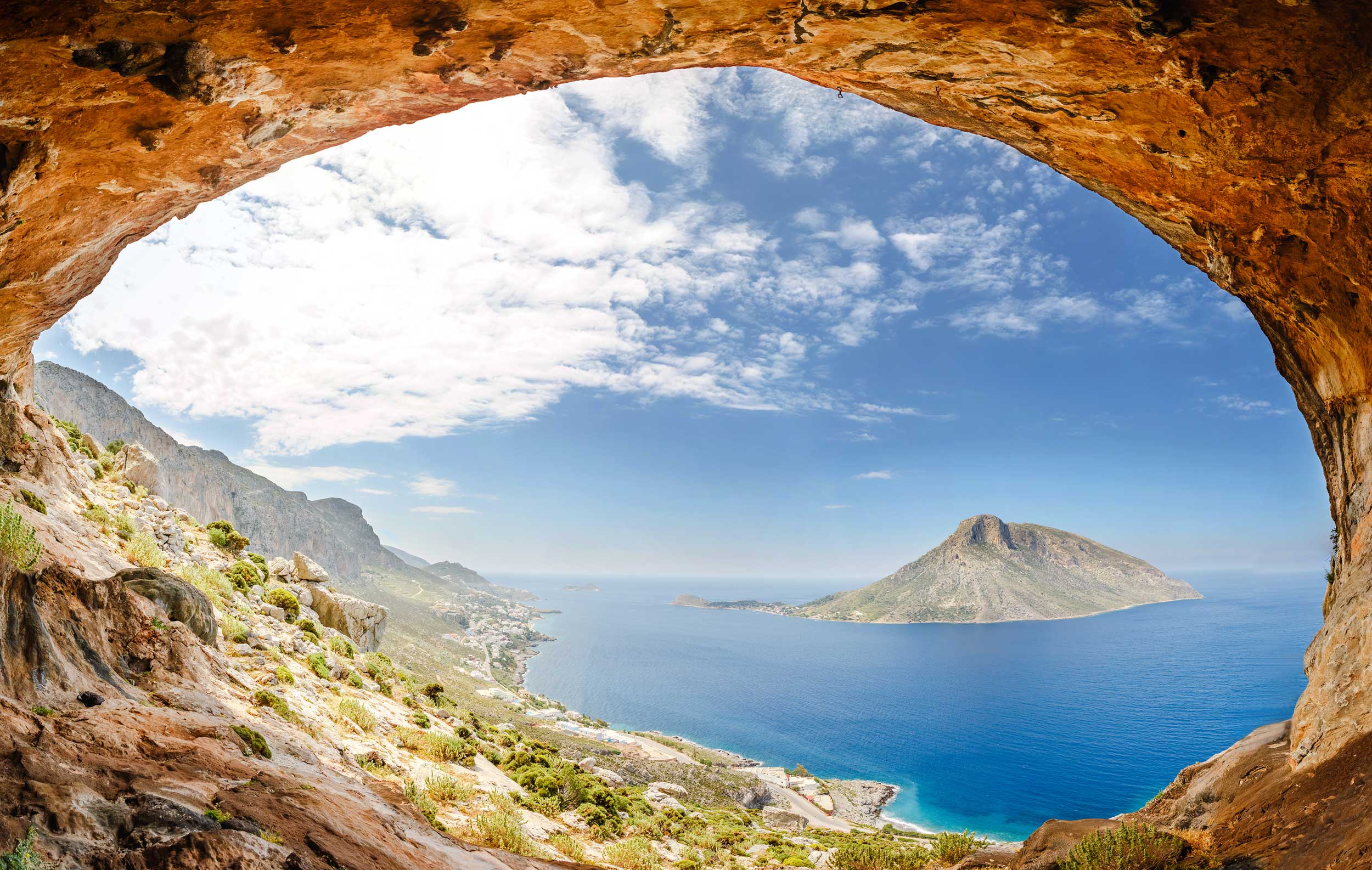 View through a stone archway to a small island out in the sea in Greece