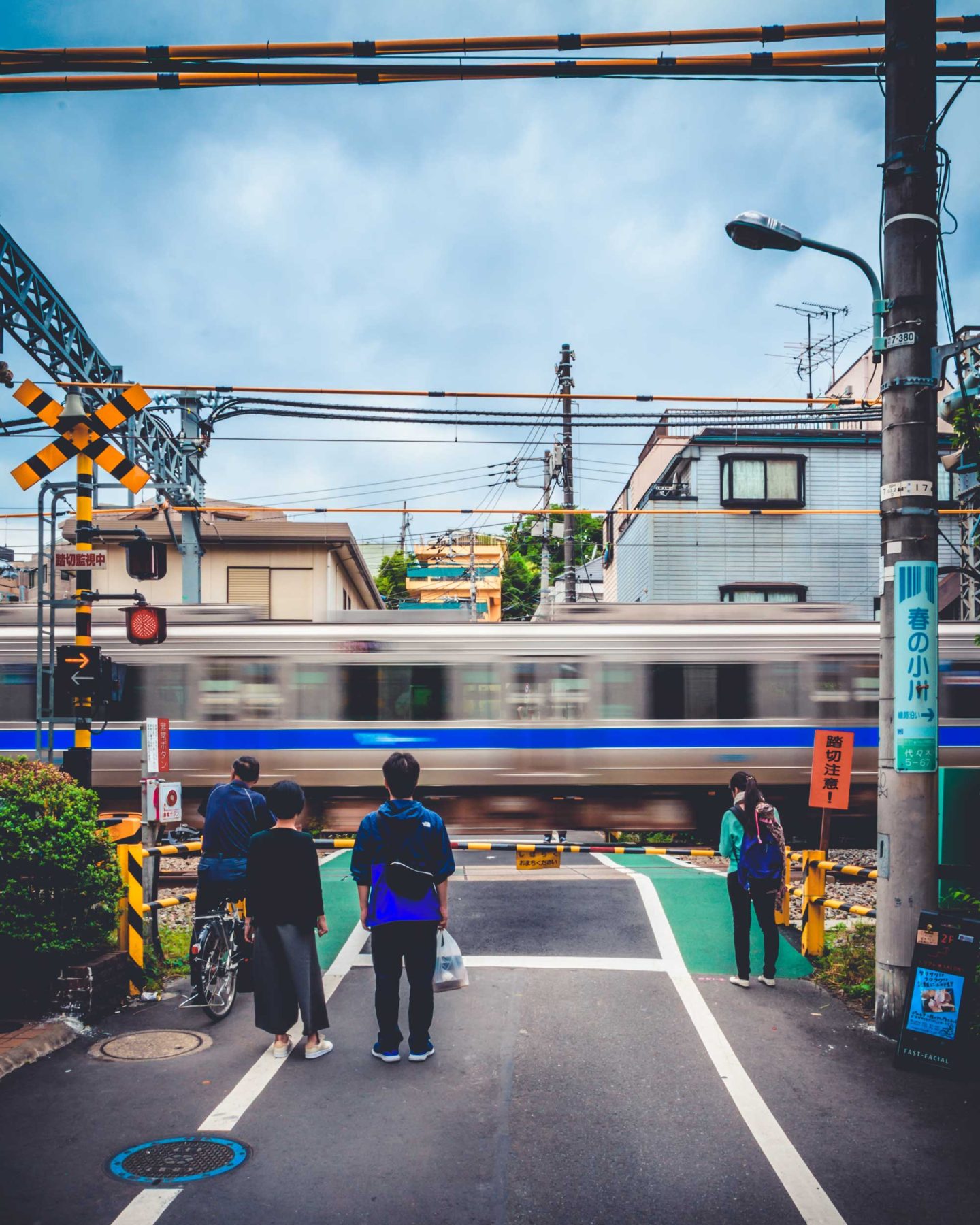 Few pedestrians waiting for a whizzing train to go past, Tokyo