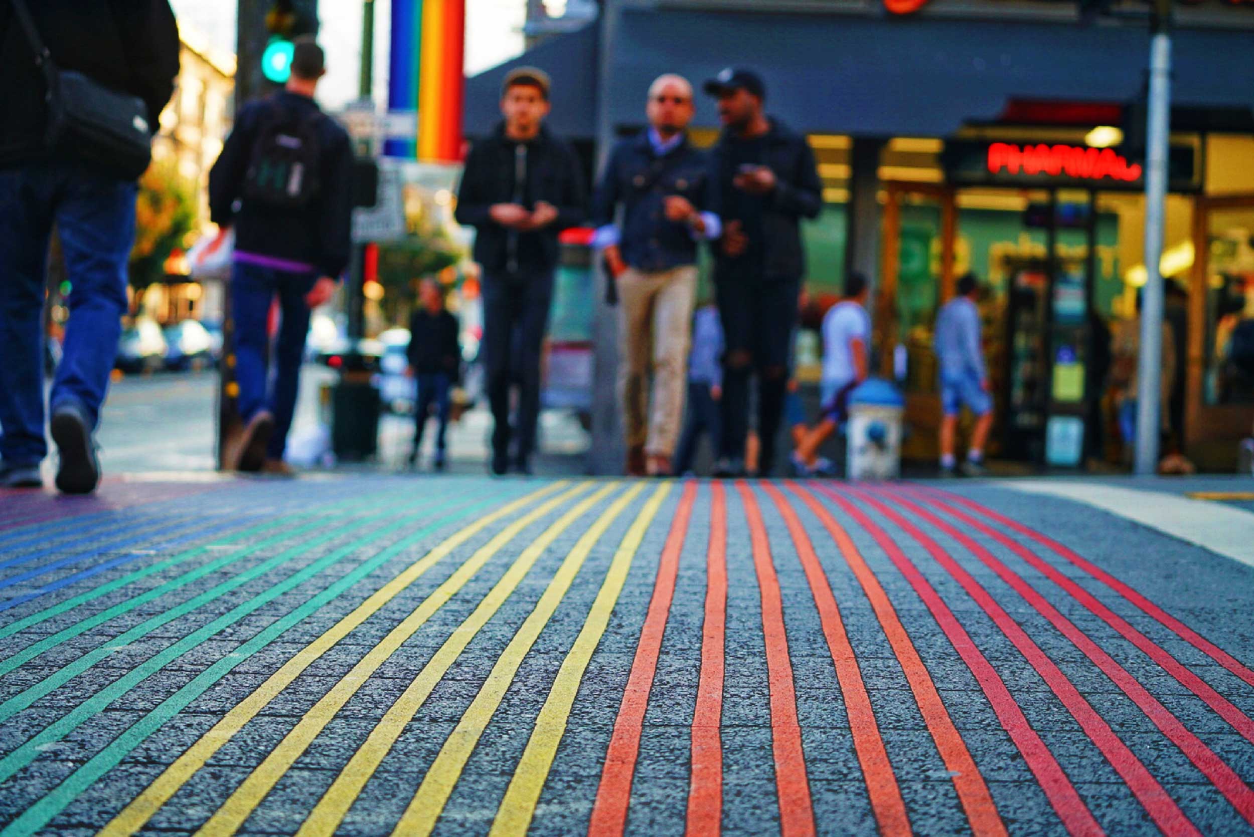 Three men walking towards camera across a multicolour-lined carpet, USA