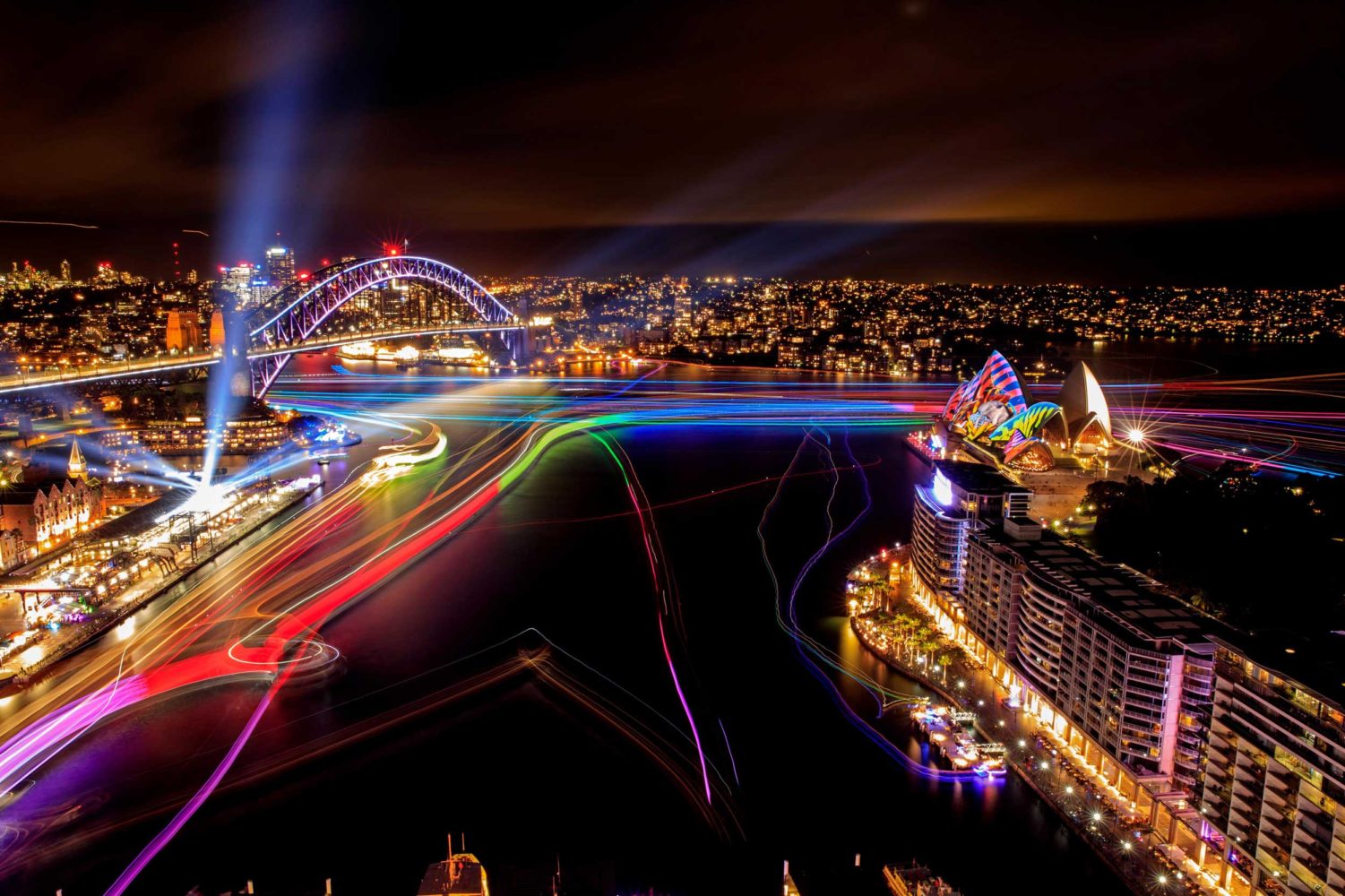 Aerial shot of a harbour with a bridge and opera house lighted up, Sydney