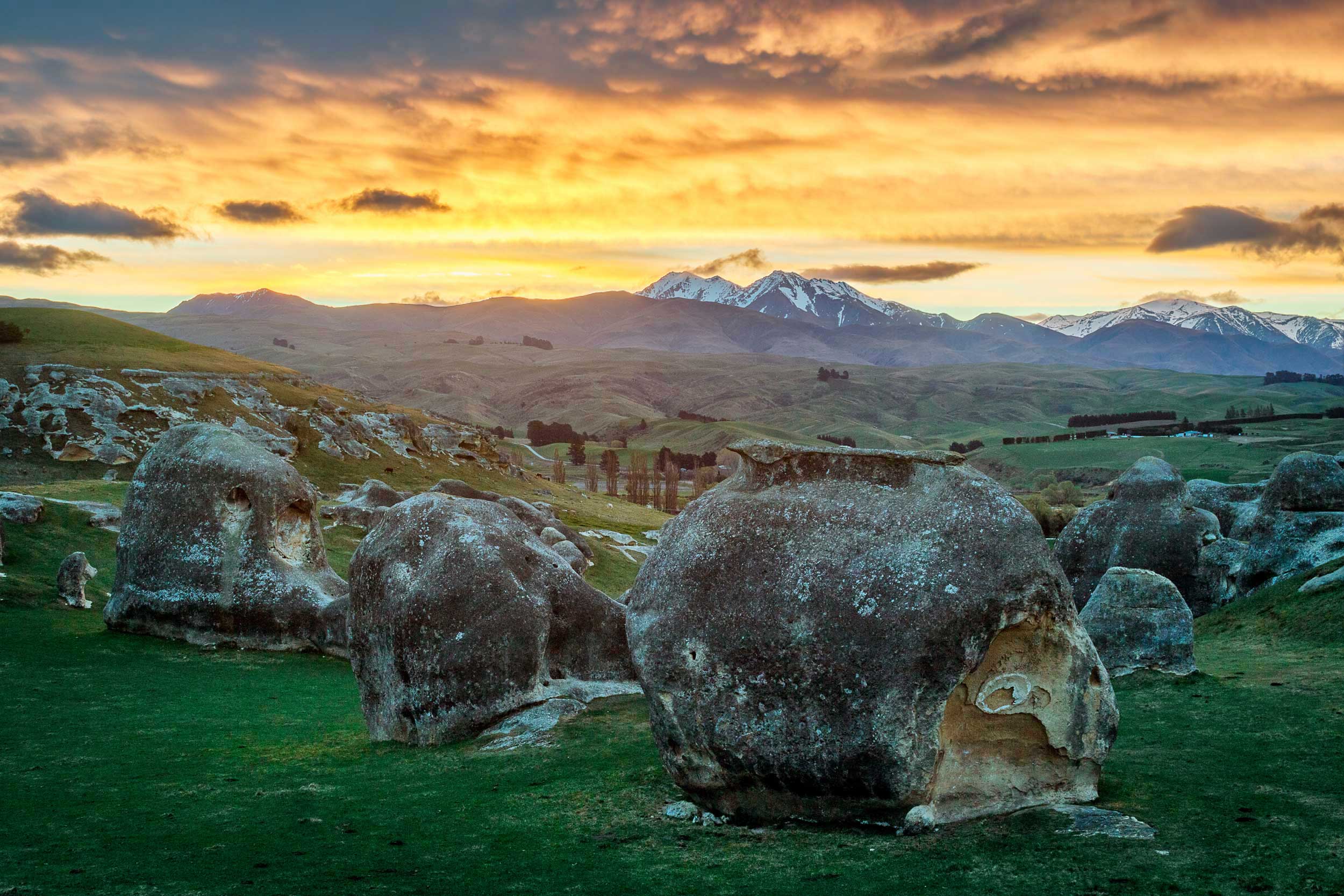 Huge boulders in a green field with a bright yellow sky, South Island, New Zealand