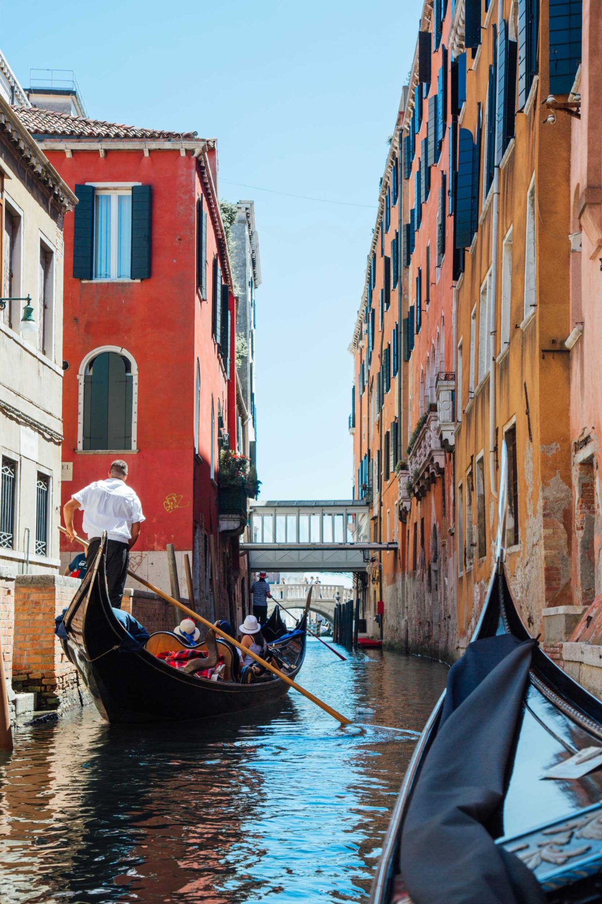 A gondola with passenger rowing through a narrow canal between colourful buildings, Venice, Italy