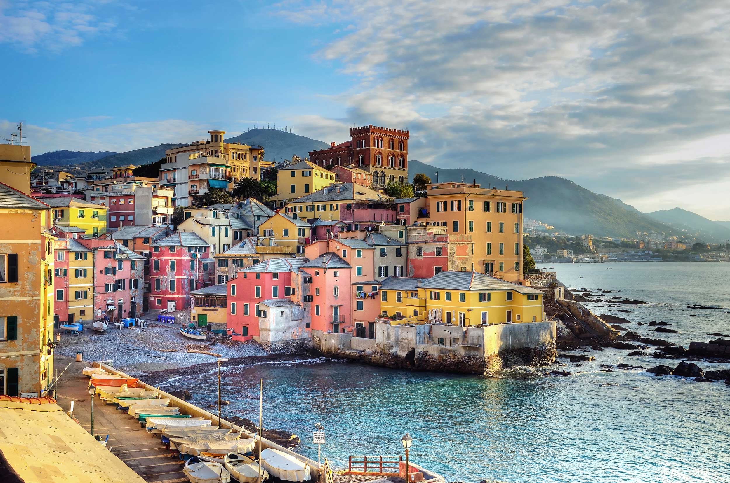 Pastel coloured buildings by the sea with landed fishing boats on the side, Genoa.